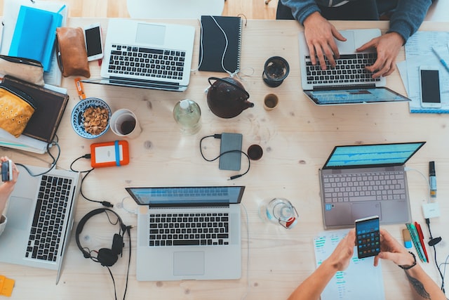 top view of a busy conference table with laptops and other peripherals